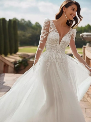 Robe de mariée coupe droite au style moderne en tulle doux, dentelle et strass. Avec un décolleté plongeant, un dos en V, des manches amovibles et une jupe fendue. Une création exclusive Adriana Alier